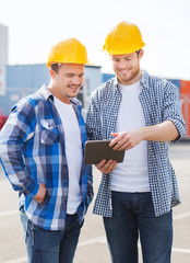smiling builders in hardhats with tablet pc