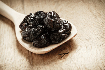 dried plums prunes on wooden spoon