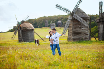 Romantic young couple on the field against old windmills