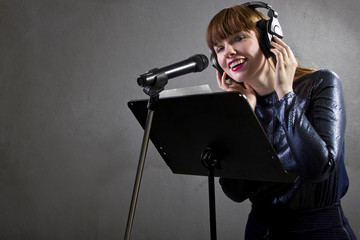 stylish female singer with microphone and reading lyrics