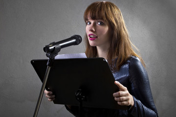 stylish female singer with microphone and reading lyrics