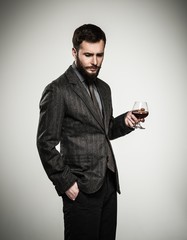 Handsome well-dressed man in jacket with glass of beverage