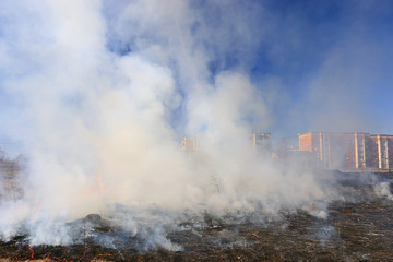 Fire burns grass field brick houses