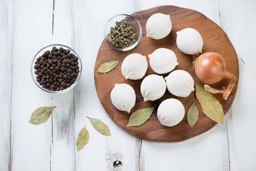 Raw khinkali, dried bay leaf, onion and pepper, high angle view