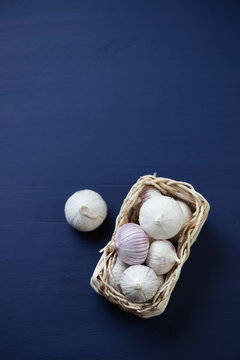Above view of a wicker tray with garlic, dark blue background