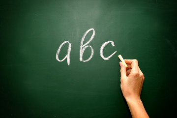 abc letters and chalk with woman hand on blackboard