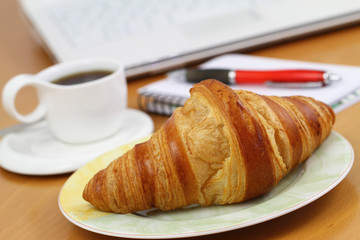 Butter croissant and black coffee on office desk