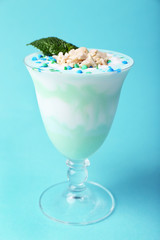 Mint milk dessert in glass bowl on color background