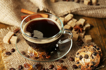Glass cup of coffee and tasty cookie on wooden background