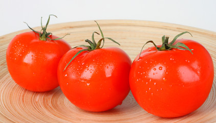 Fresh red tomatoes on wooden plate
