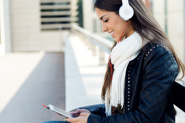Beautiful girl listening to music in city.