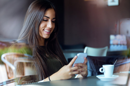 Beautiful Girl Using Her Mobile Phone In Cafe.