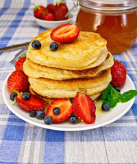 Flapjacks with strawberries and blueberries on blue tablecloth