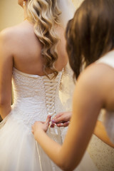 girlfriend tying corset bride on wedding