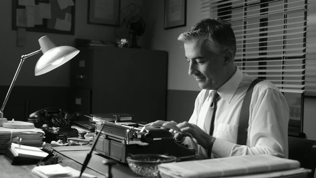 Smiling vintage reporter working at office desk and typing on a 