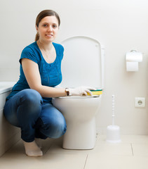 Smiling girl  cleaning toilet bowl