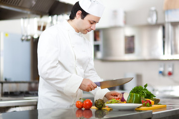 Friendly chef preparing vegetables in his kitchen
