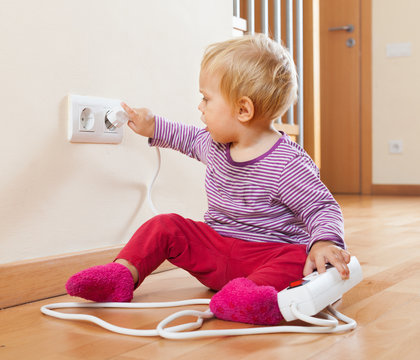Toddler playing with extension cord and  electric outlet
