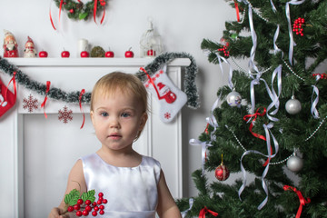 Cute little girl holds a red berries  near  New Year  Christmas