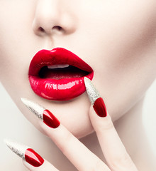 Make-up und Maniküre. Rote lange Nägel und rote glänzende Lippen