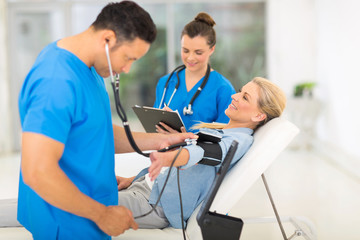 Obraz premium medical doctor taking mid age woman's blood pressure