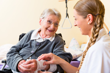 Pflegerin kümmert sich um Seniorin in Altenheim  - obrazy, fototapety, plakaty