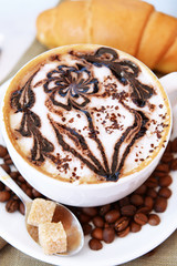 Cup of coffee with cute drawing on table, close up