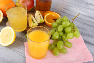 glasses of juice with fresh fruits on grey wooden table