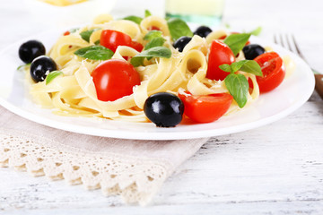 Spaghetti with tomatoes, olives and basil leaves