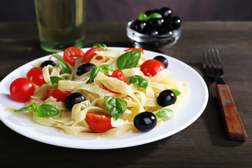 Spaghetti with tomatoes, olives and basil leaves