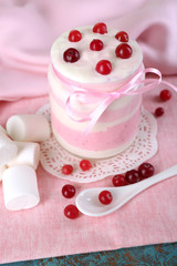 Raspberry milk dessert in glass jar, on color wooden background