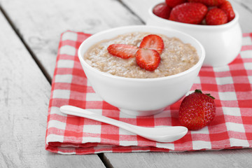 Tasty oatmeal with strawberry on table close-up