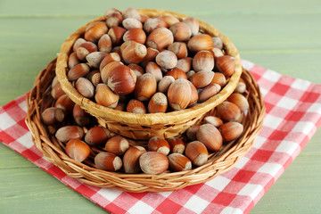 Hazelnuts in wicker basket on wooden background
