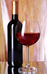 Red wine glass and bottle of wine on bright background