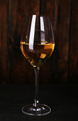 Wineglass with white wine on wooden background