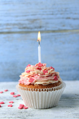 Delicious birthday cupcake on table on wooden background