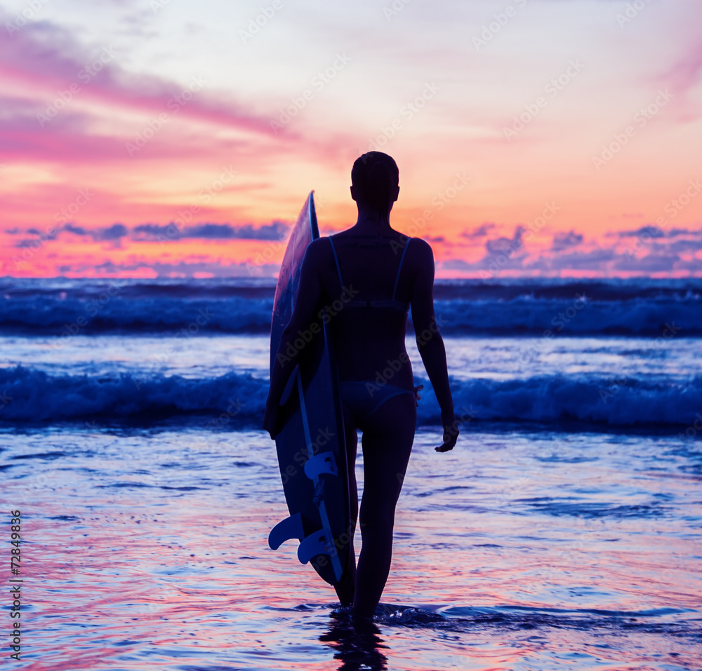 Wall mural Young woman surfer with board