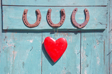 three old rusty horseshoe luck symbol and red heart on door - 72850468