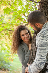 Naklejka premium happy young couple leaning against a tree enjoying the autumn in