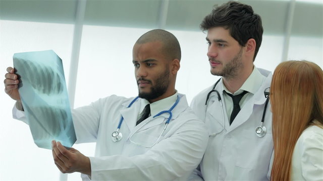 Three confident doctor examining x-ray snapshot of lungs