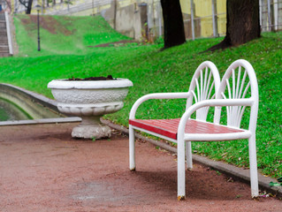 red-white wooden bench in the park on the green grass background