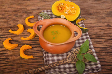 Pumpkin soup in clay pot with fresh pumpkins for healthy