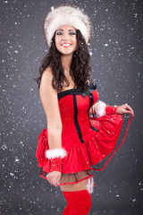 sexy santa girl in red dress over snowy Christmas background