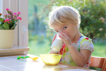 Little girl having breakfast in sunny kitchen