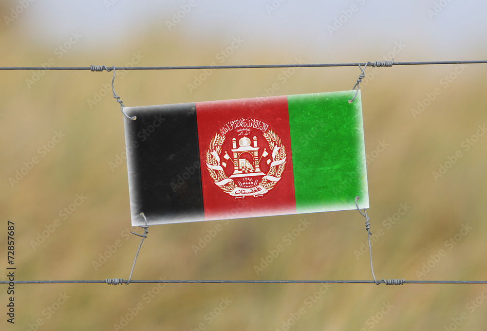 Wall mural Border fence - Old plastic sign with a flag