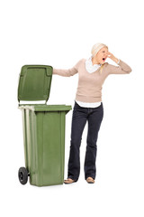 Vertical shot of a woman opening a stinky trash can