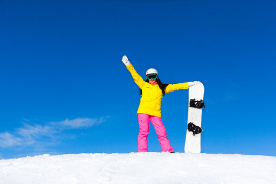 snowboarder girl raised arms standing hold snowboard