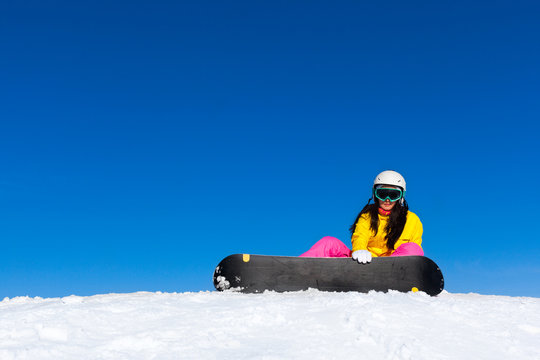snowboarder woman sitting on snow mountain slope