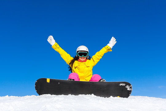 snowboarder woman sitting on snow mountain slope happy raised
