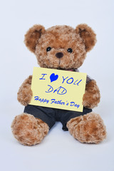 Teddy bear holding a yellow sign that says I love dad